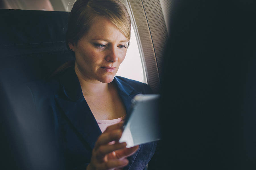 Woman using tablet pc in plane. Photograph by Guido Mieth