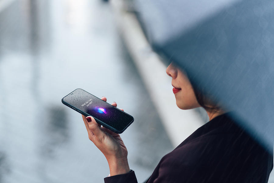 Woman using voice assistant on smartphone in the rain Photograph by Oscar Wong
