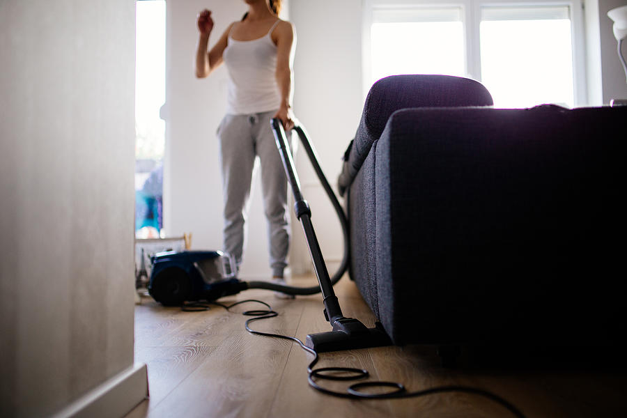 Woman vacuuming living room Photograph by South_agency