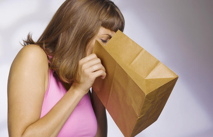 Woman Vomiting Into Paperbag Photograph by Peter Dazeley