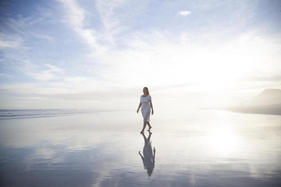Woman walking on beach Photograph by Alistair Berg
