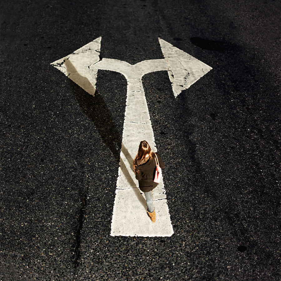 Woman walking on directional arrow of a road Photograph by Westend61
