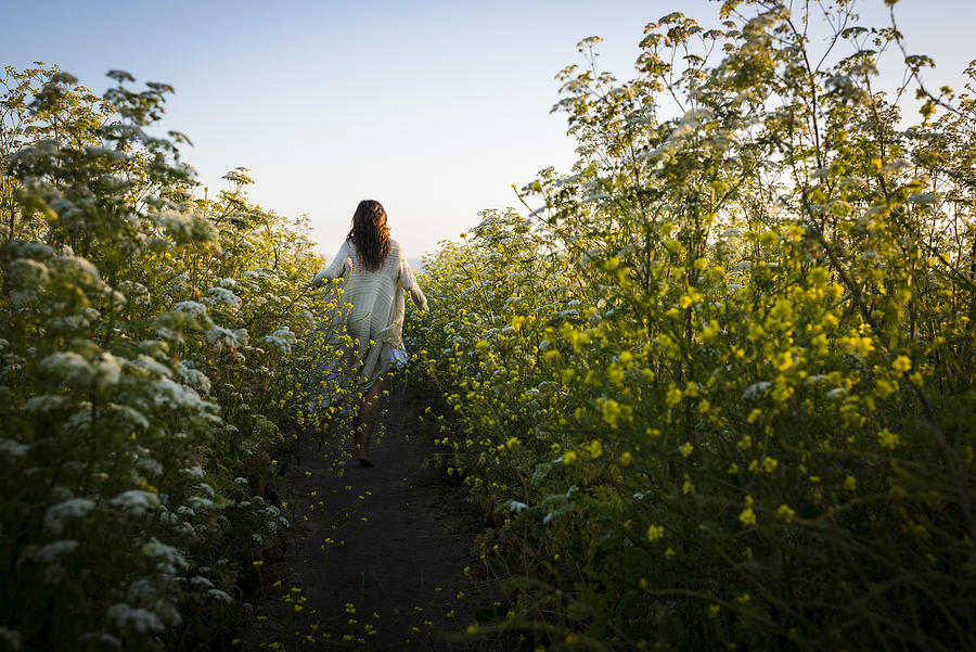 Woman walking through field of wildflowers Photograph by Lindsay Upson