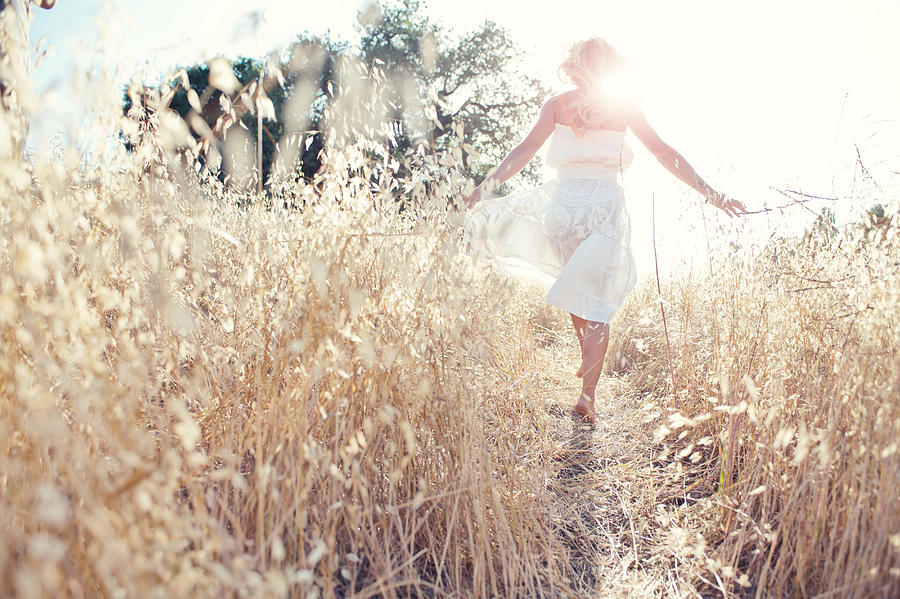 Woman walking through field touching grasses Photograph by Jade Brookbank