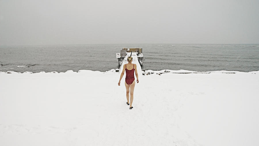 Woman walking towards freezing ocean in bathing su Photograph by David Trood
