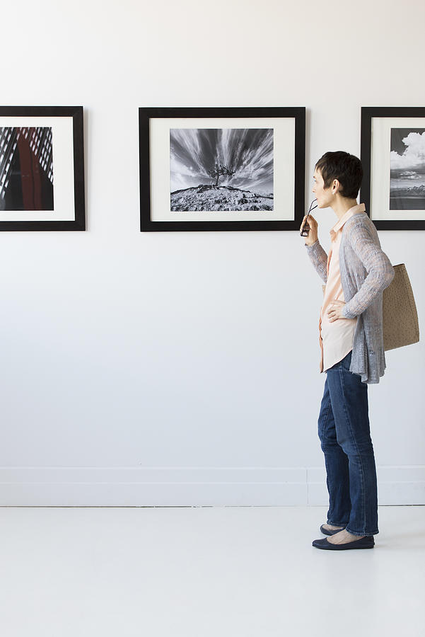 Woman watching photographs in art gallery Photograph by Tetra Images