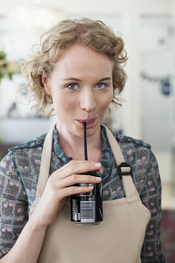 Woman wearing apron drinking soda Photograph by Tomas Rodriguez