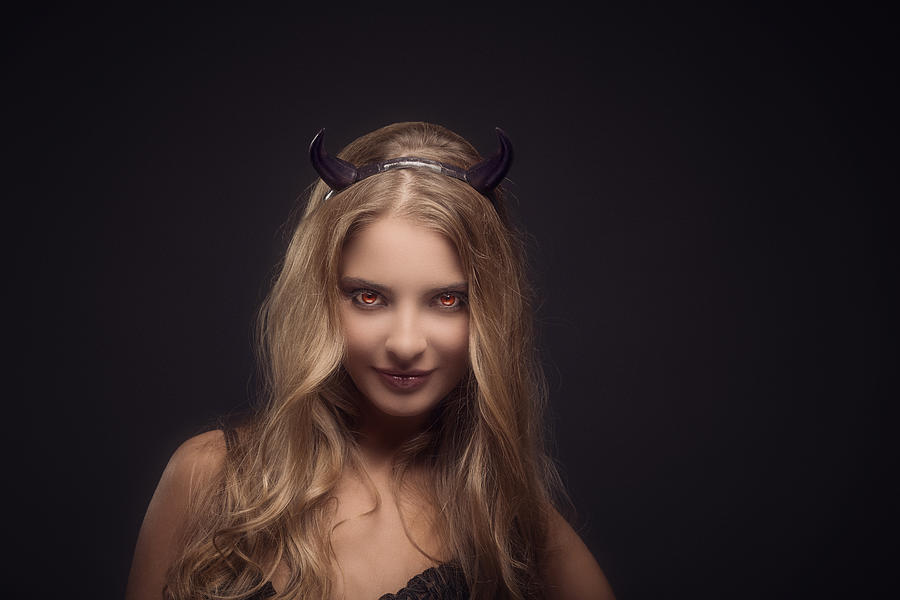 Woman wearing devil horns Photograph by Peter Zelei Images