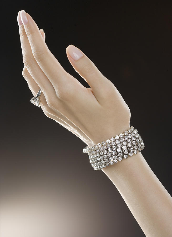 Woman wearing diamond ring and bracelets, close-up Photograph by Jamie Grill