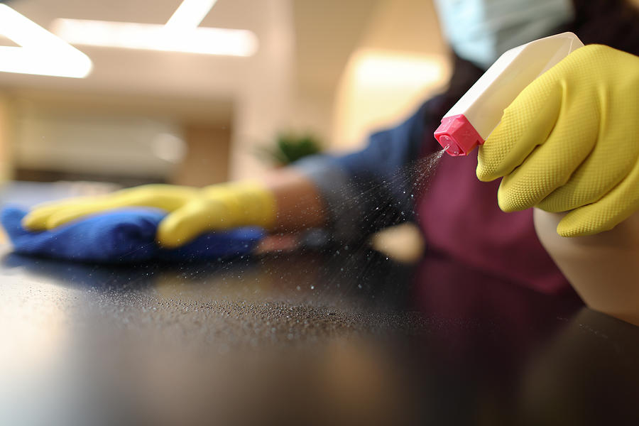 Woman wearing gloves cleaning desktop Photograph by Bernie_photo