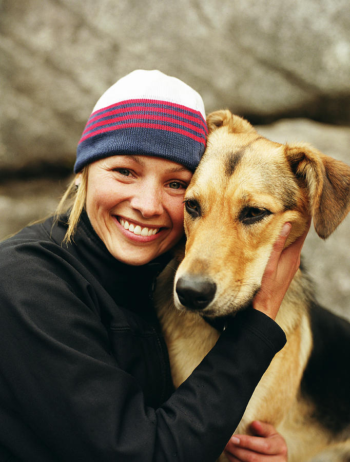 Woman wearing knit cap, hugging dog, portrait Photograph by Mike Powell
