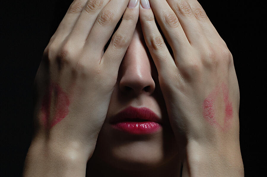 Woman wearing lipstick and covering her face Photograph by Image Source