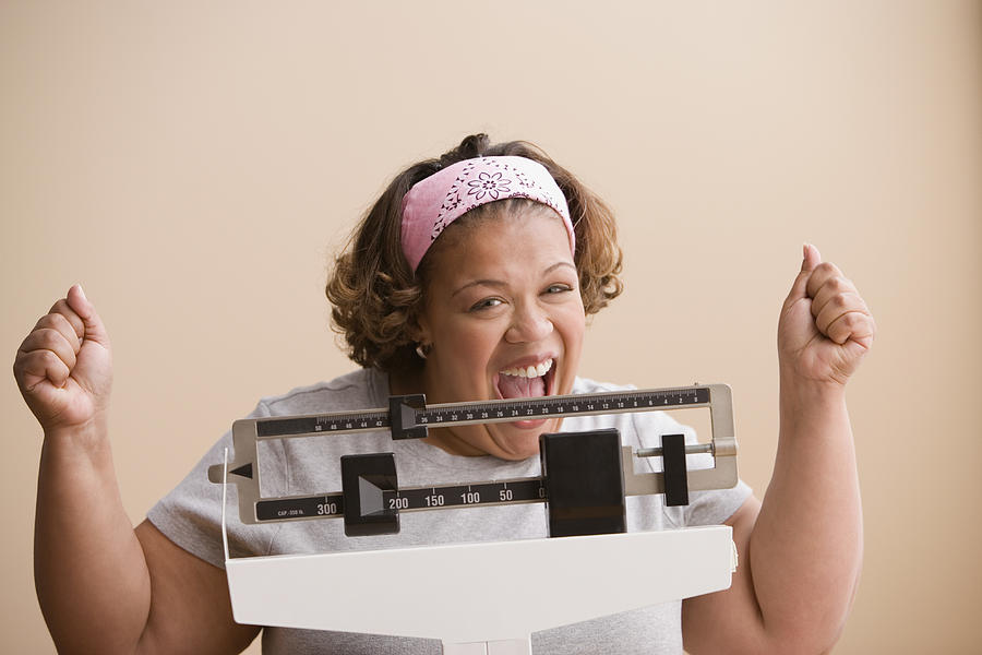 Woman weighing herself Photograph by Jose Luis Pelaez Inc