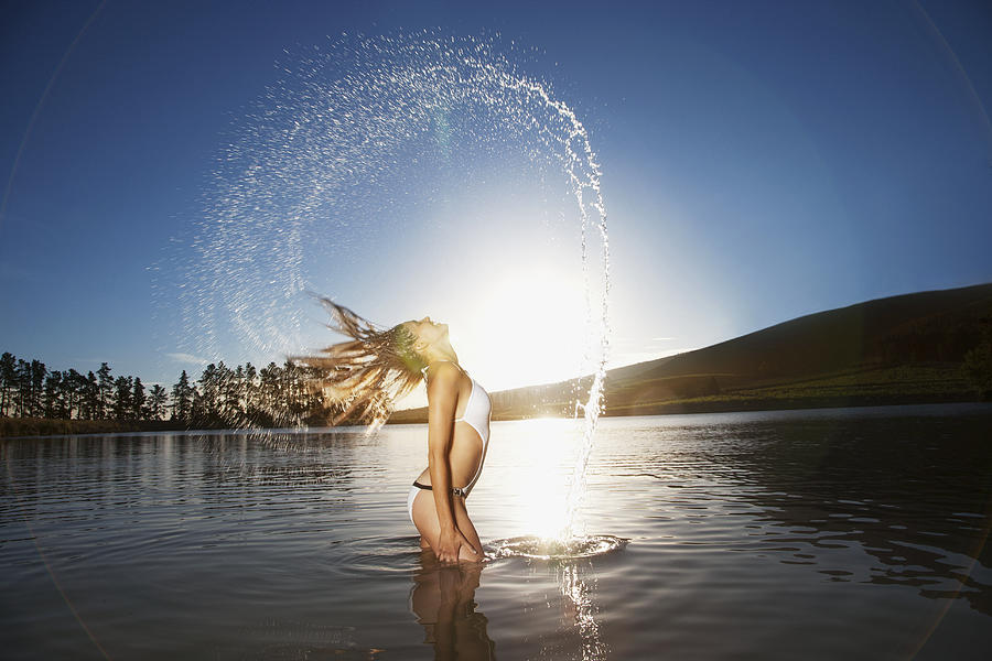 Woman wetting and flipping her hair in lake Photograph by Rob Daly