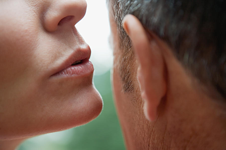 Woman whispering into mans ear Photograph by Image Source