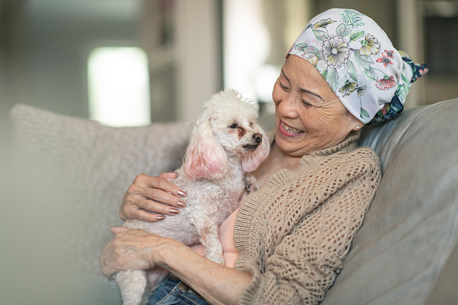 Woman with cancer relaxes at home with her pet dog Photograph by FatCamera