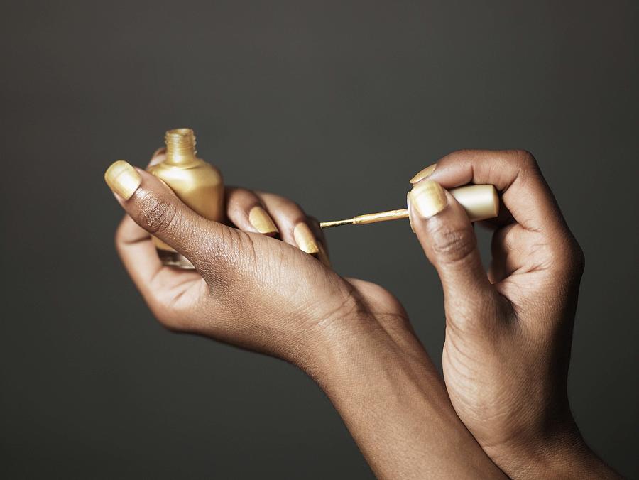 Woman with gold nail polish Photograph by Jupiterimages
