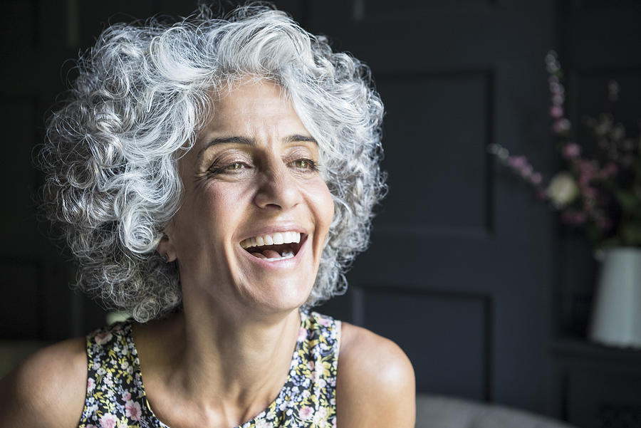 Woman with grey curly hair looking away and laughing Photograph by JohnnyGreig