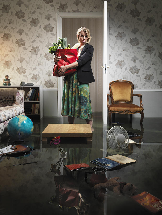 Woman With Grocery In Flooded Room Photograph by Henrik Sorensen
