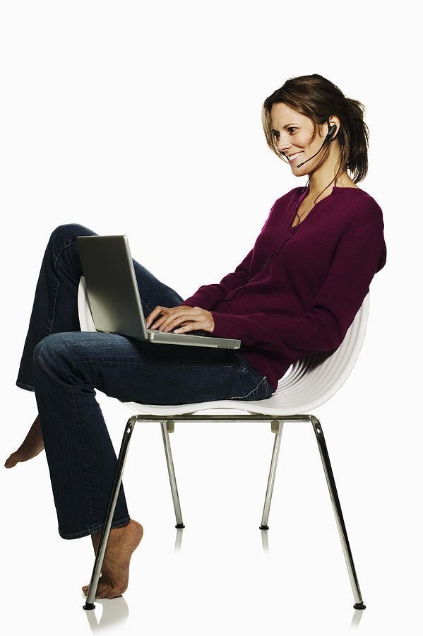 Woman with laptop computer and earpiece Photograph by Jupiterimages