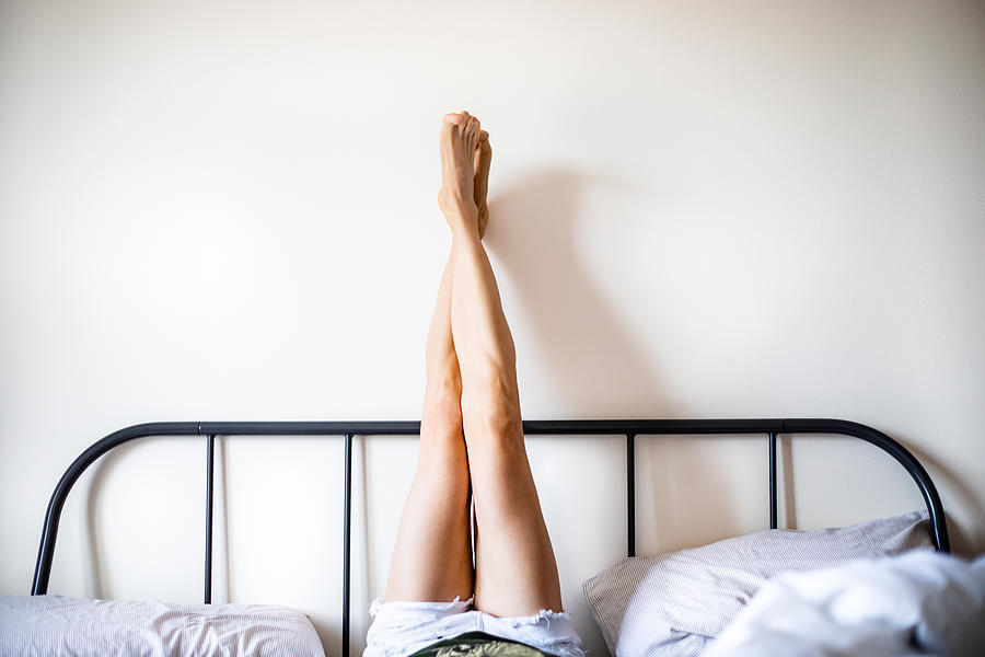 Woman with Legs Raised wearing white shorts lying on bed Photograph by Photographer, Basak Gurbuz Derman