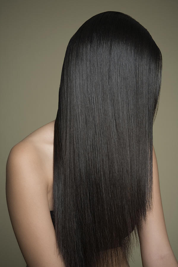 Woman with long, shiny hair covering face. Photograph by Andreas Kuehn Woman with long, shiny hair covering face. Photograph by Andreas Kuehn