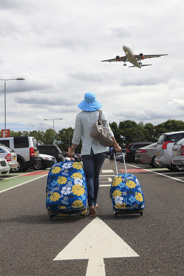 Woman with suitcases in airport car park Photograph by Peter Cade