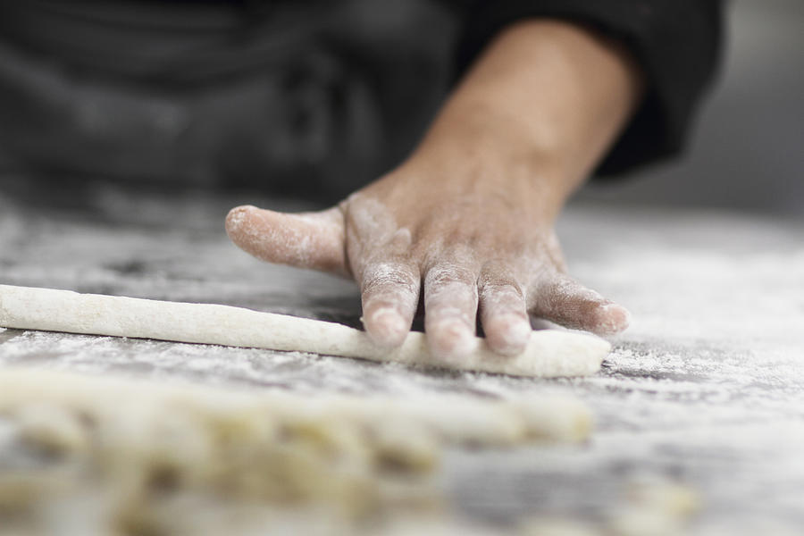 Woman working in restaurant kitchen, cropped hand rolling pastry Photograph by Sigrid Gombert