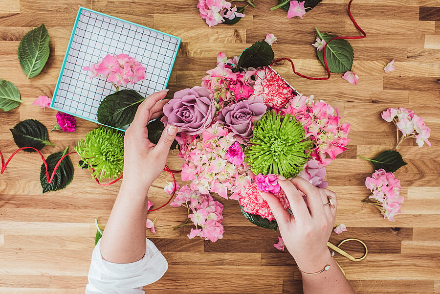 Woman wrapping valentines flowers gifts overhead Photograph by Knape