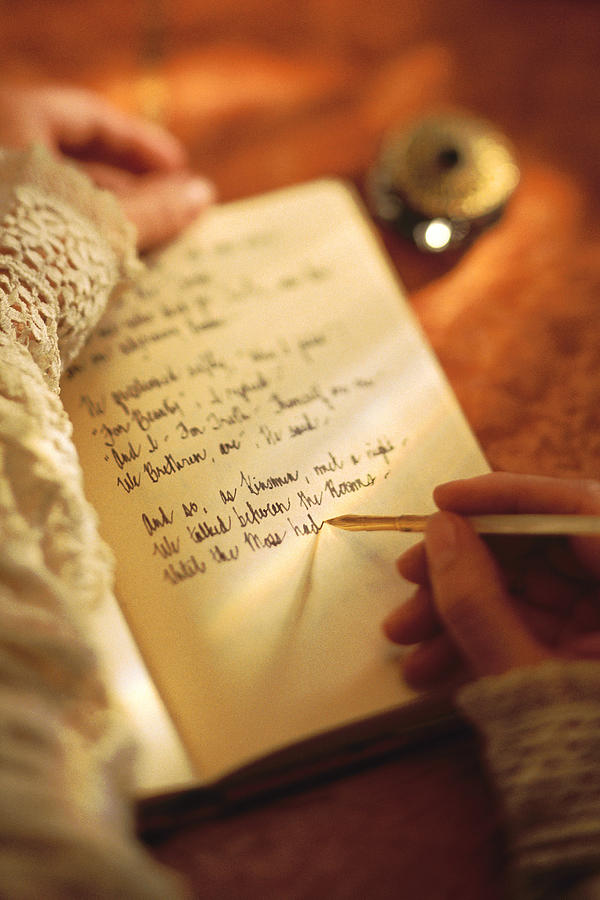 Woman writing in diary with ink pen Photograph by Comstock