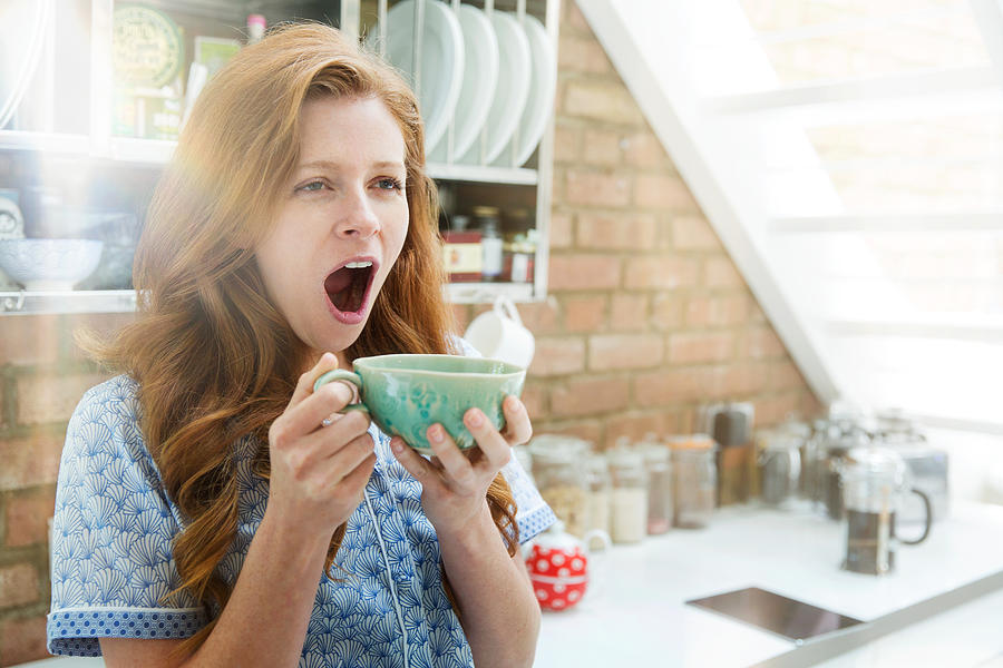 Woman yawning with coffee Photograph by Tim Robberts