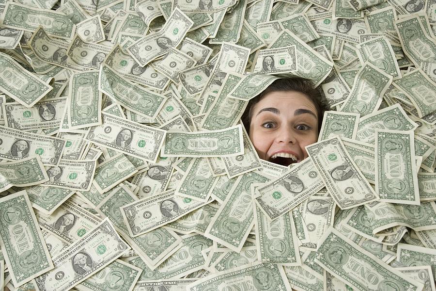Womans face peeking out of a pile of money Photograph by John M Lund Photography Inc