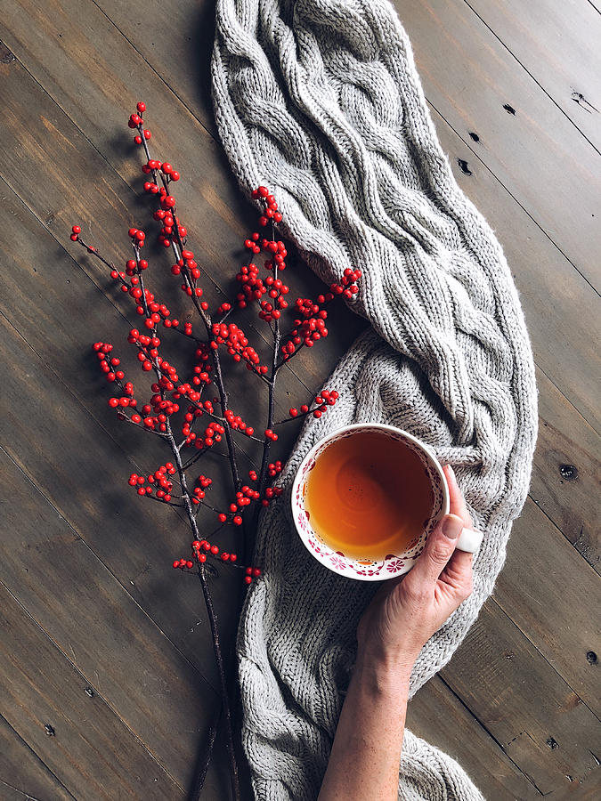 Womans hand holding a cup of herbal tea with berries and a knitted scarf Photograph by JuliaK