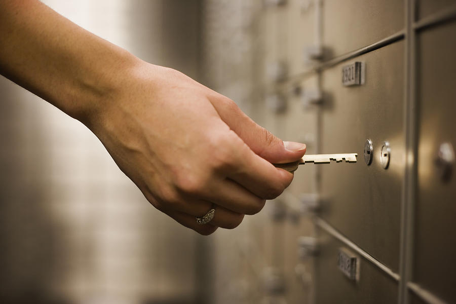 Womans hand holding key to safety deposit box Photograph by ColorBlind