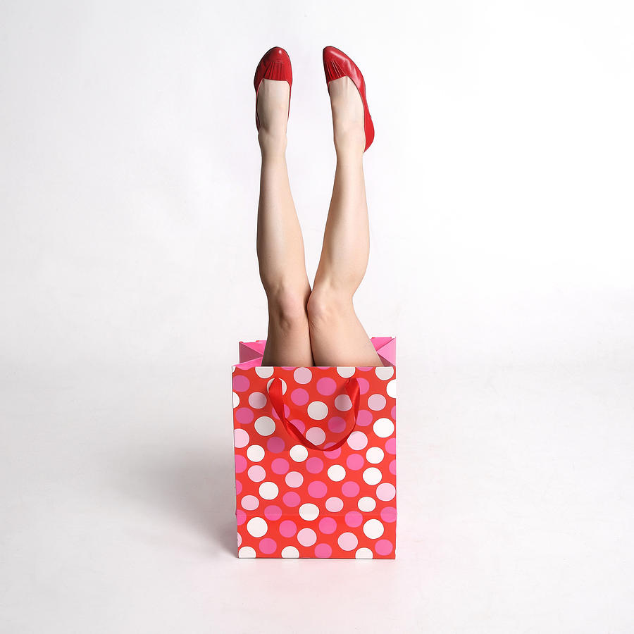 Womans legs coming out of a festive gift  bag Photograph by Lisa Noble Photography