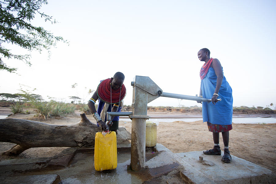 Women collecting clean water from borehole in desert. Samburu. Kenya. Photograph by Hugh Sitton