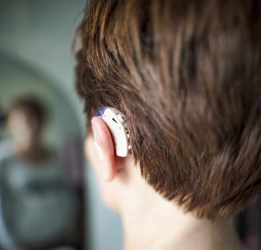 Women inserting hearing aid. Medical concept Photograph by Mikroman6