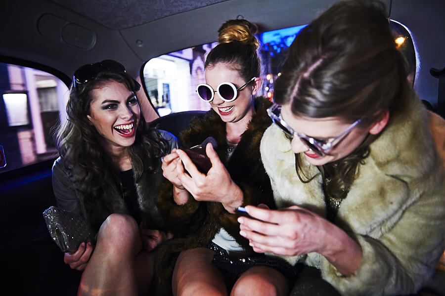 Women laughing together in taxi Photograph by Mike Harrington