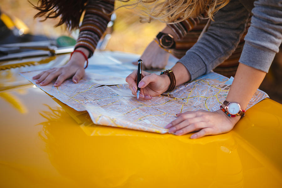 Women on summer road trip reading map for directions Photograph by Wundervisuals