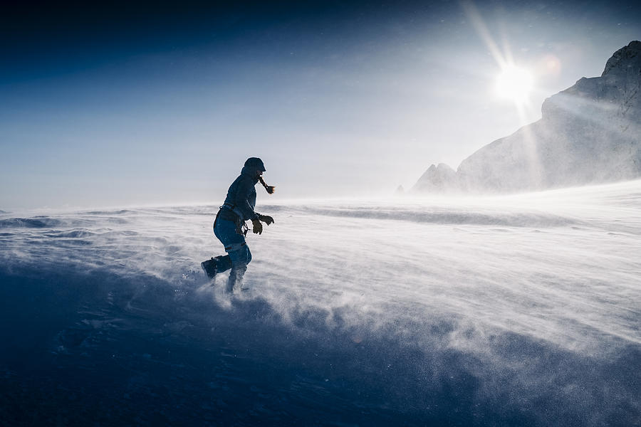 Women runs across glacier in strong winds Photograph by Alex Ratson