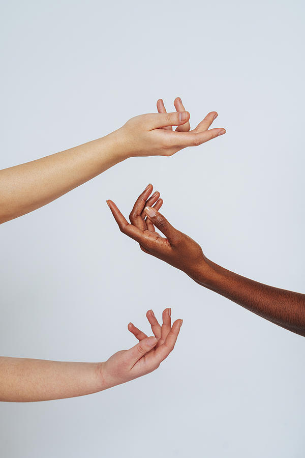 Women stretching hands toward each other against white background Photograph by Westend61