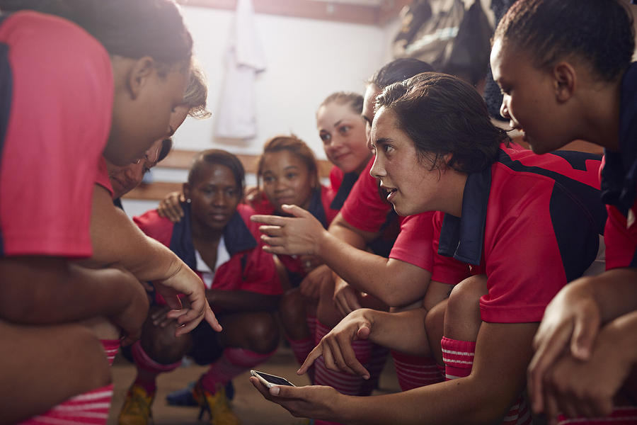 Womens rugby players looking at phone before game Photograph by Klaus Vedfelt