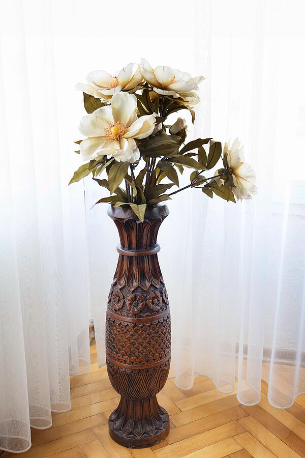 Wooden carved vase with artifical flowers in daylight. Photograph by Emreturanphoto