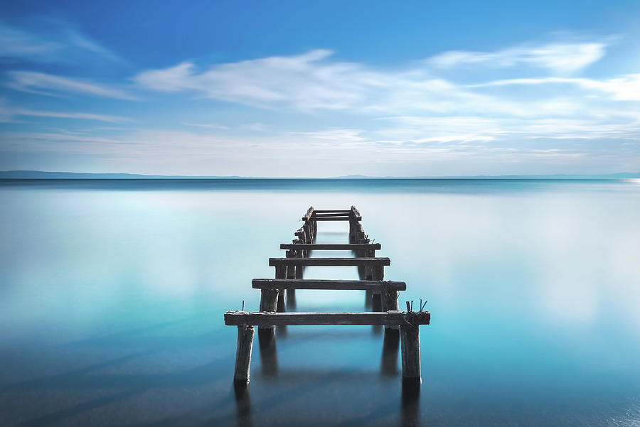 Wooden pier or jetty remains on a blue lake. Long Exposure. Photograph by Stefano Orazzini