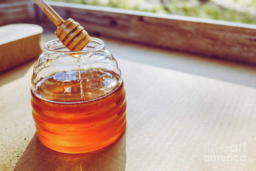 Wooden spoon for honey, dripping in the jar, remedy to cure winter colds, copy space. Photograph by Joaquin Corbalan