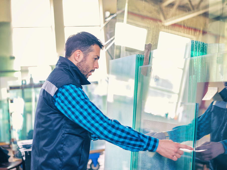 Worker handling glass sheet in warehouse Photograph by Bluecinema