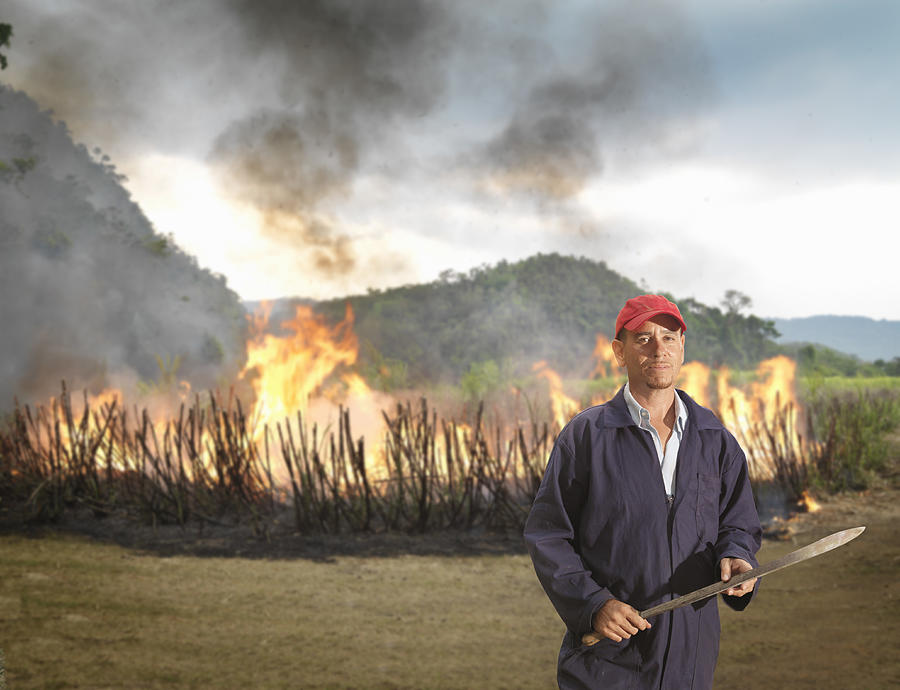 Worker In Front Of Burning Sugar Cane Photograph by Monty Rakusen