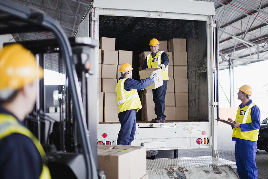 Workers unloading boxes from truck Photograph by Hybrid Images