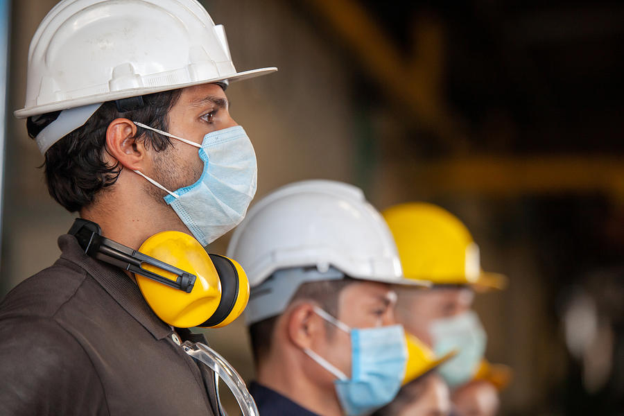 Workers wear protective face masks for safety in machine industrial factory. Photograph by Nikom1234