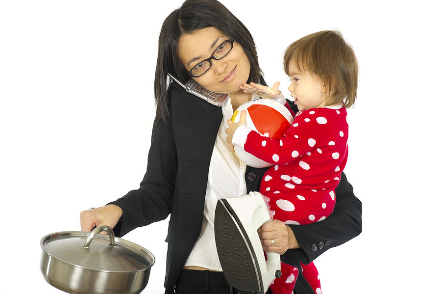 Working mom juggles a child and household chores Photograph by stockstudioX